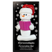 Ornament of white snowman in red hat holding a pink book, on display backing card.