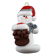 Ornament of white snowman in red hat holding a brown dog and a pair of scissors.