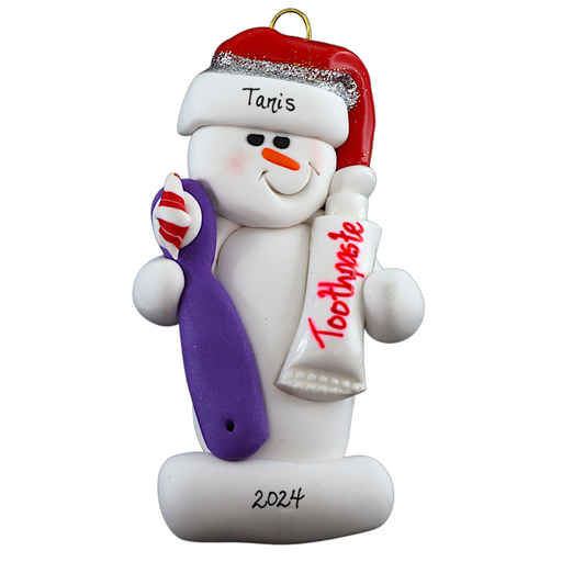 Ornament of white snowman in red hat holding a toothbrush and toothpaste, personalized with name.