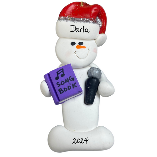 Ornament of white snowman in red hat holding a microphone and purple music book, personalized with name.