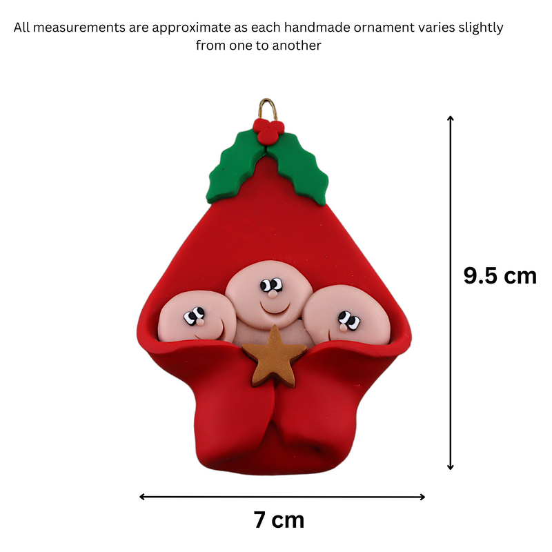 Ornament with triplet infant heads poking out of a red baby blanket, graphed to show size (7x9.5cm).