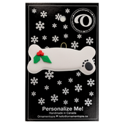 Ornament of dog bone with holly and paw print, on display backing card.