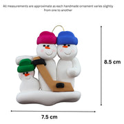 Family ornament with 3 white snowmen in bright hats, holding a hockey stick, graphed to show size (7.5x8.5cm).