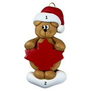 Tan bear in red festive hat with maple leaf ornament, numbered 1-2 for personalization.