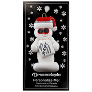 Ornament of white snowman in red hat and sunglasses holding a movie script, on display backing card.