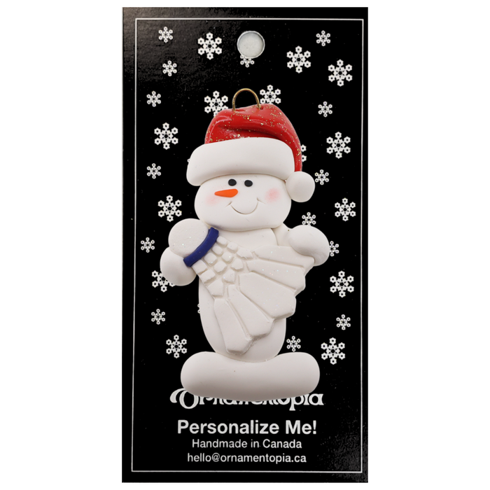 Ornament of white snowman in red hat holding a white badminton birdie, on display backing card.