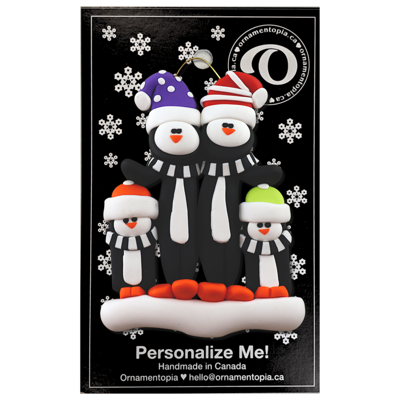 Family ornament with 4 black and white penguins in colourful festive hats, on display backing card.