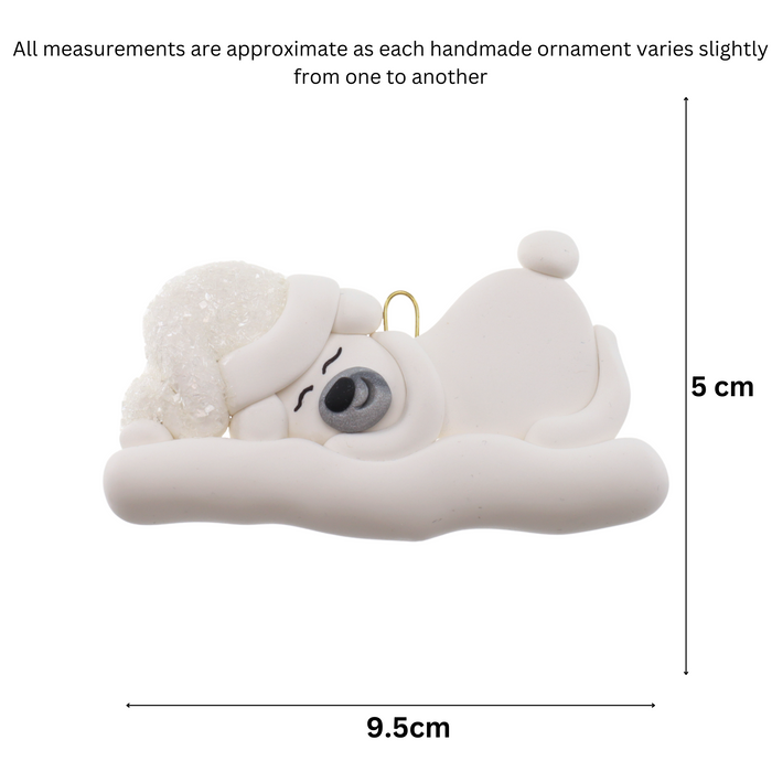 Ornament of white sleeping polar bear baby in a white sparkling hat, graphed to show size (9.5x5cm).