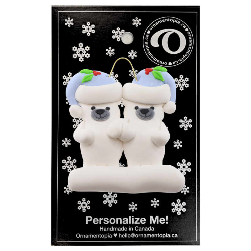 Family ornament with 2 polar bear figures in blue Christmas hats, on display backing card.