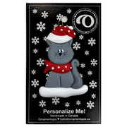 Ornament of grey cat in red and white polka dot Christmas hat and scarf, on display backing card.