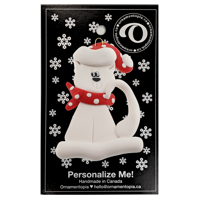 Ornament of white cat in red and white polka dot Christmas hat and scarf, on display backing card.