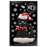Ornament of black cat in red and white polka dot Christmas hat and scarf, on display backing card.