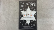 Family ornament with 3 white snowmen stacked on top of a glitter white snowflake, shown on backing card and Christmas tree.