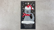 Ornament of grey cat in red and white polka dot Christmas hat and scarf, shown on backing card and Christmas tree.