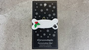 Ornament of dog bone with holly and paw print,shown on backing card and decorated Christmas tree.