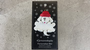 Ornament of white dog in red hat hanging on a white bone, shown on backing card and Christmas tree.