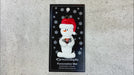 Ornament of white snowman in red hat holding several small rocks, shown on backing card and Christmas tree.
