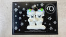 Family ornament with 2 polar bear figures in blue Christmas hats, shown on backing card and Christmas tree.