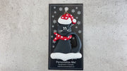 Ornament of black cat in red and white polka dot Christmas hat and scarf, shown on backing card and Christmas tree.