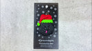 Black frowning lump of coal wearing red festive hat ornament, shown on backing card and Christmas tree.