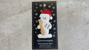 Ornament of white snowman in red hat holding a baseball bat and a baseball, shown on backing card and Christmas tree.