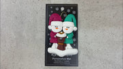 Ornament of snowman couple in red and green shirts and hats with a brown cat in Christmas hat, shown on backing card and Christmas tree.