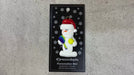 Ornament of white snowman in red hat holding a tennis paddle and ball, shown on backing card and Christmas tree.