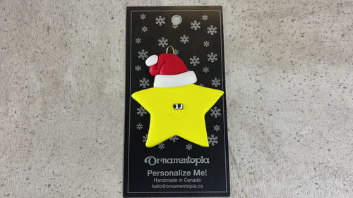 Yellow star in red Christmas hat ornament, shown on backing card and Christmas tree.