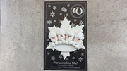 Family ornament with 4 white snowmen stacked on top of a glitter white snowflake, shown on backing card and Christmas tree.