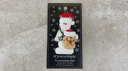 Ornament of white snowman in red hat holding a tan dog and stethoscope, shown on backing card and Christmas tree.