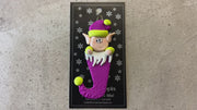 Elf poking out of magenta stocking ornament, shown on backing card and Christmas tree.