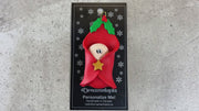 Ornament with an infant head poking out of a red baby blanket, shown on backing card and Christmas tree.