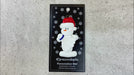 Ornament of white snowman in red hat holding a white badminton birdie, shown on backing card and Christmas tree.