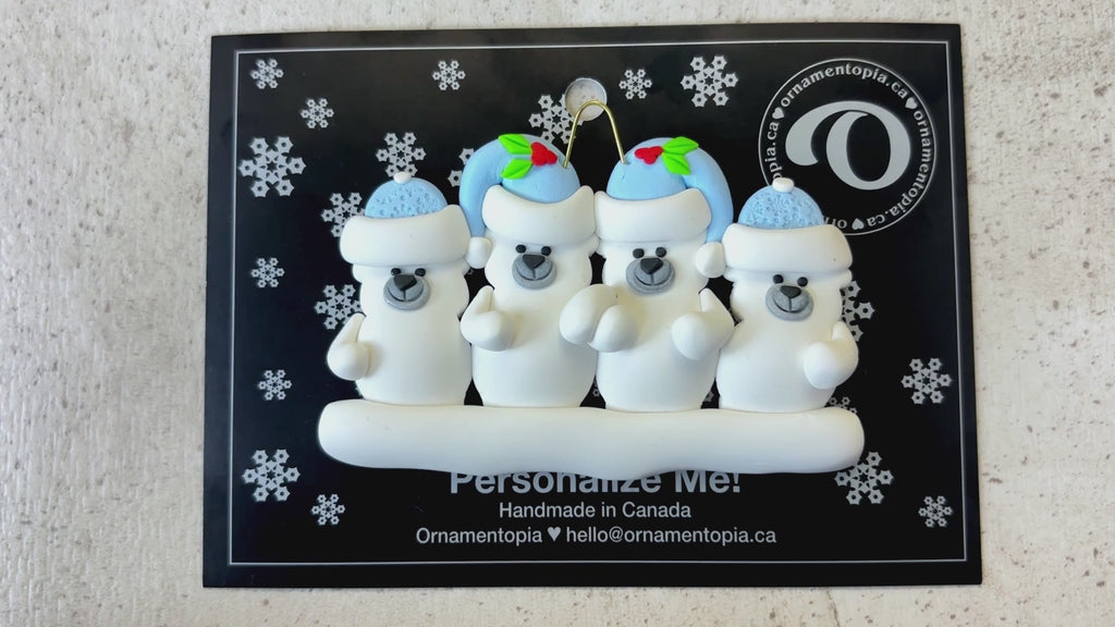 Family ornament with 4 polar bear figures in blue Christmas hats, shown on backing card and Christmas tree.