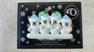 Family ornament with 4 polar bear figures in blue Christmas hats, shown on backing card and Christmas tree.