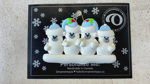 Family ornament with 4 polar bear figures in blue Christmas hats, shown on backing card and Christmas tree.