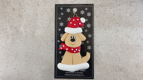 Ornament of tan dog in a red and white polka dot Christmas hat and scarf, shown on backing card and Christmas tree.