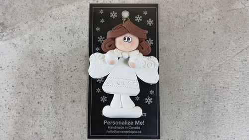 Angel wearing white with brown hair ornament, shown on backing card and Christmas tree.
