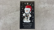 Ornament of white snowman in red hat holding a cow and stethoscope, shown on backing card and Christmas tree.