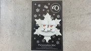Family ornament with 2 white snowmen stacked on top of a glitter white snowflake, shown on backing card and Christmas tree.