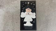 Angel wearing white with black hair ornament, shown on backing card and Christmas tree.