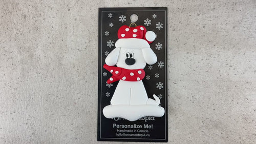Ornament of white dog in a red and white polka dot Christmas hat and scarf, shown on backing card and Christmas tree.