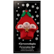 Ornament with triplet infant heads poking out of a red baby blanket, on display backing card.
