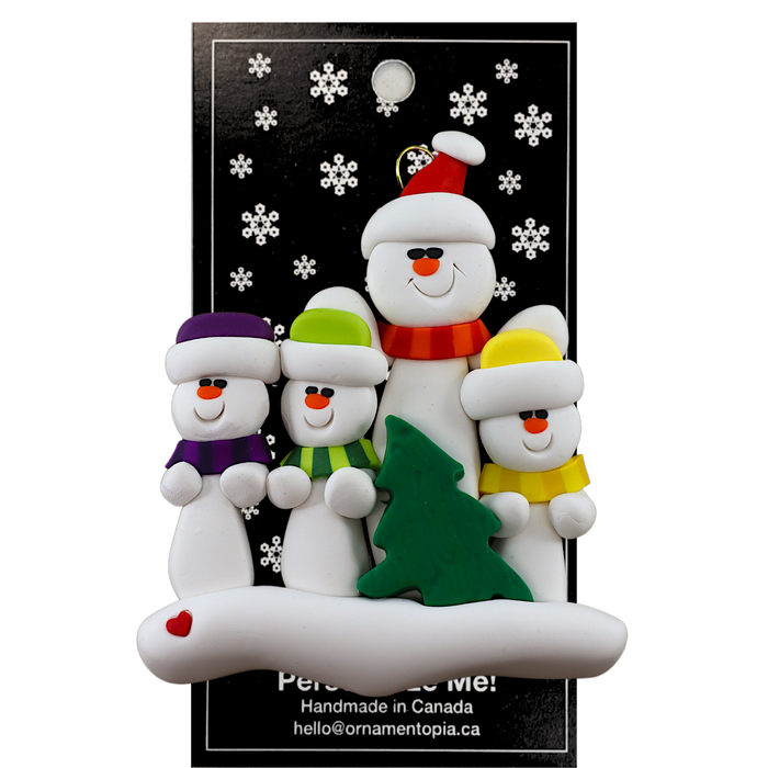 Family ornament with 1 large and 3 small white snowmen in bright scarves, with green Christmas tree, on display backing card.