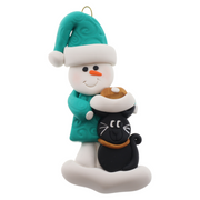 Ornament of snowman in a green shirt and hat with black cat in Christmas hat.