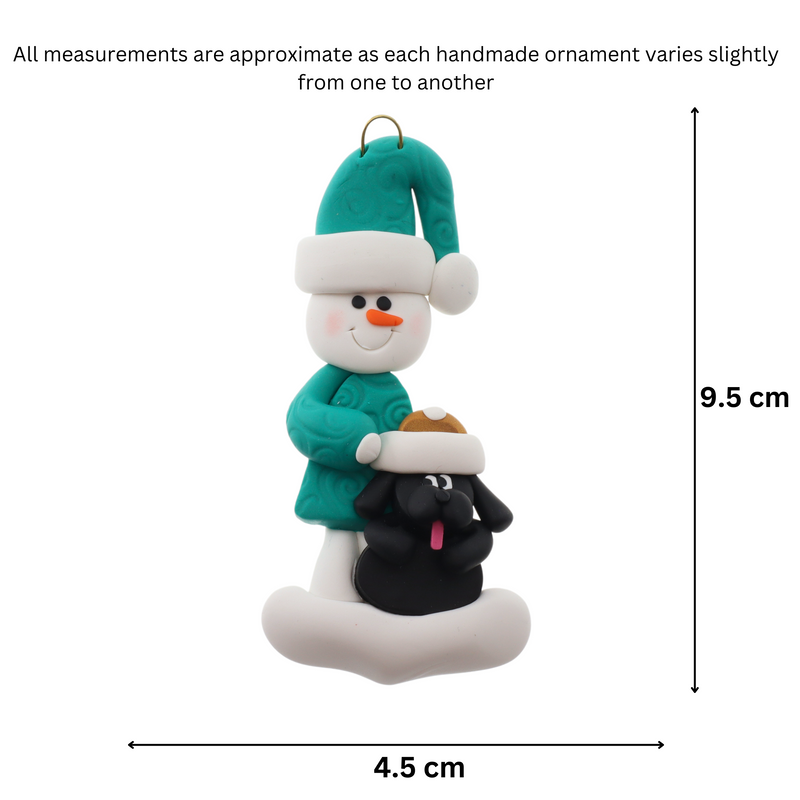 Ornament of snowman in green shirt and hat with black dog in Christmas hat, graphed to show size (4.5x9.5cm).