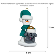 Ornament of snowman in green shirt and hat with grey dog in Christmas hat, graphed to show size (5x11cm).