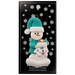 Ornament of snowman in green shirt and hat with white dog in Christmas hat, on display backing card.