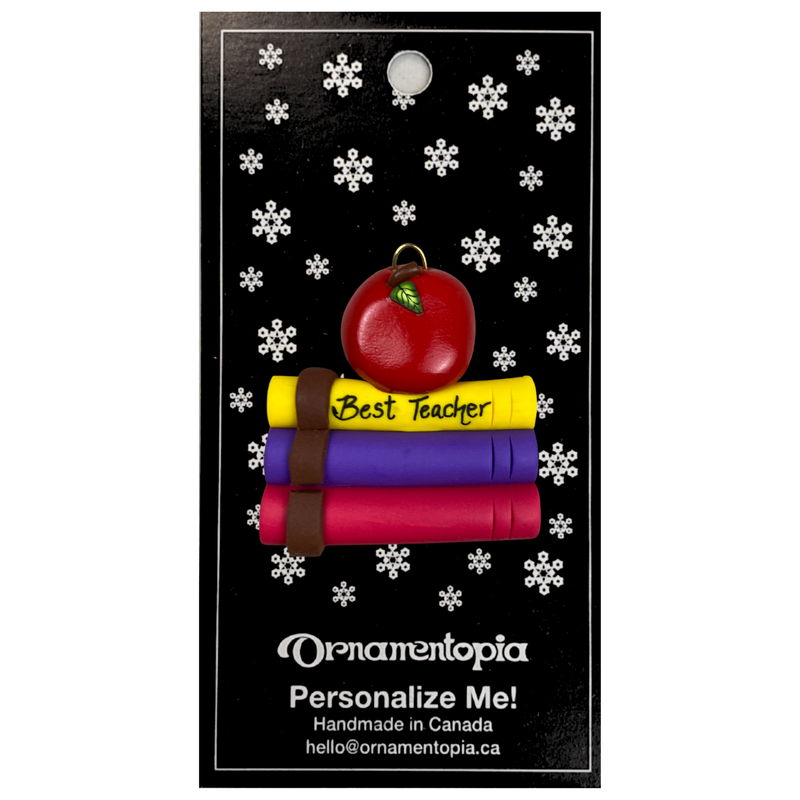 Stack of books and red apple teacher appreciation ornament, on display backing card.